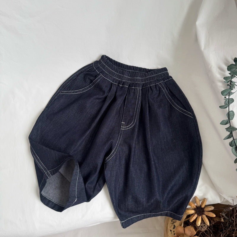 Dark blue denim shorts with elastic waist, white contrast stitching, pockets, and a cuffed hem on one leg.