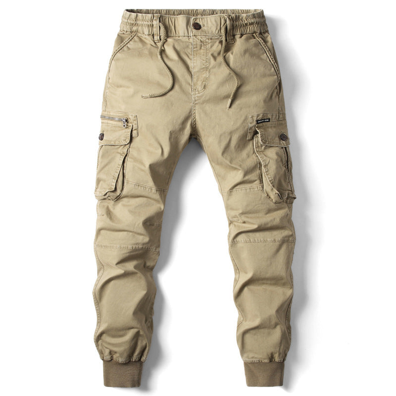 Khaki cargo pants in cotton with elastic waist, drawstring, zippered pockets, and ribbed cuffs.