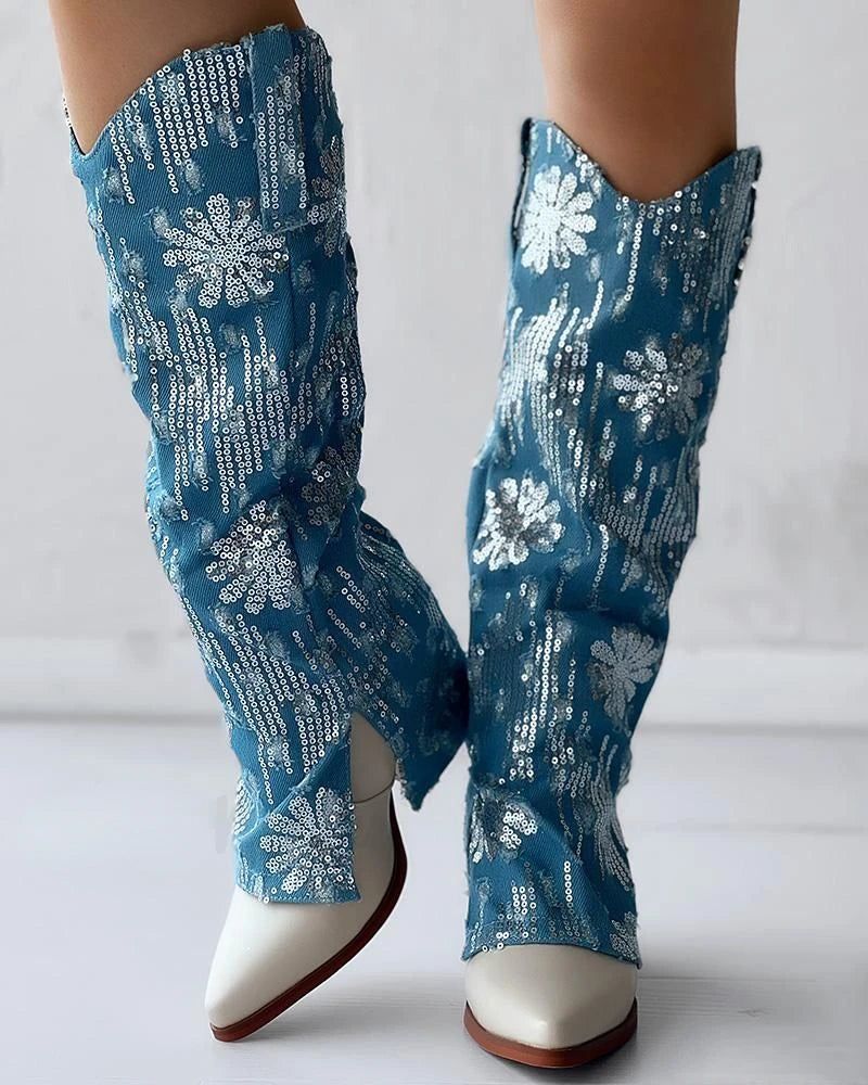 Blue denim cowboy boots with a silver sequin floral pattern, knee-high style, and white pointed-toe heels.