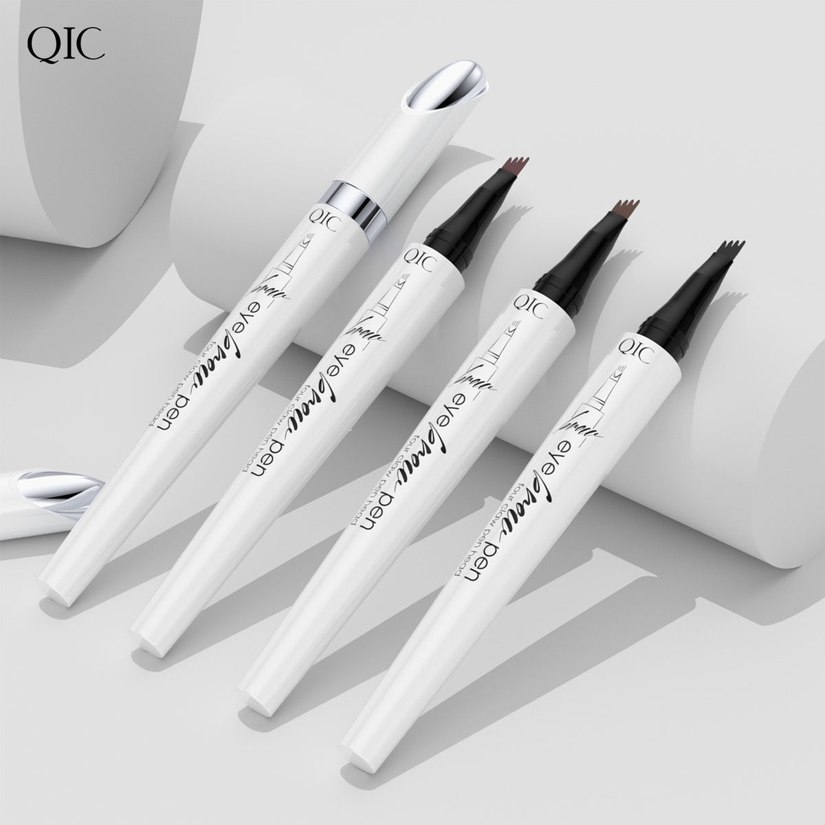 Four white QIC eyebrow pens with four-prong tips displayed vertically on a white cylindrical platform.