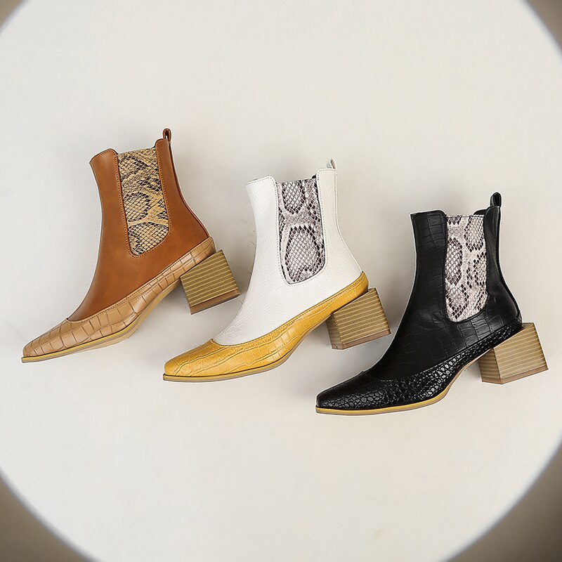 Three Chelsea boots in brown, white, and black with snake-print elastic panels, faux-croc toes, and chunky block heels.