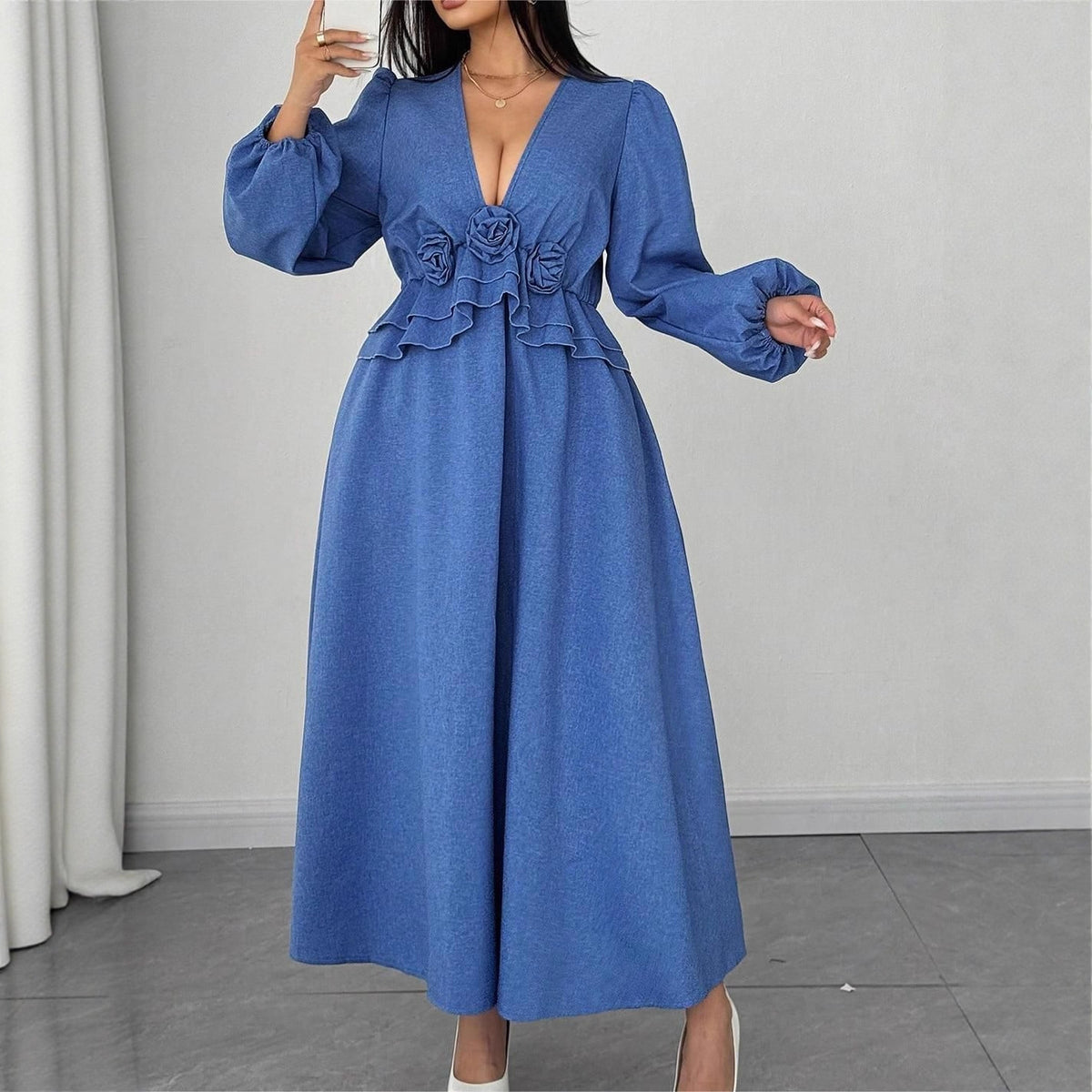 Long blue denim dress with V-neck, long sleeves, ruffled waist, and three fabric roses on the front.