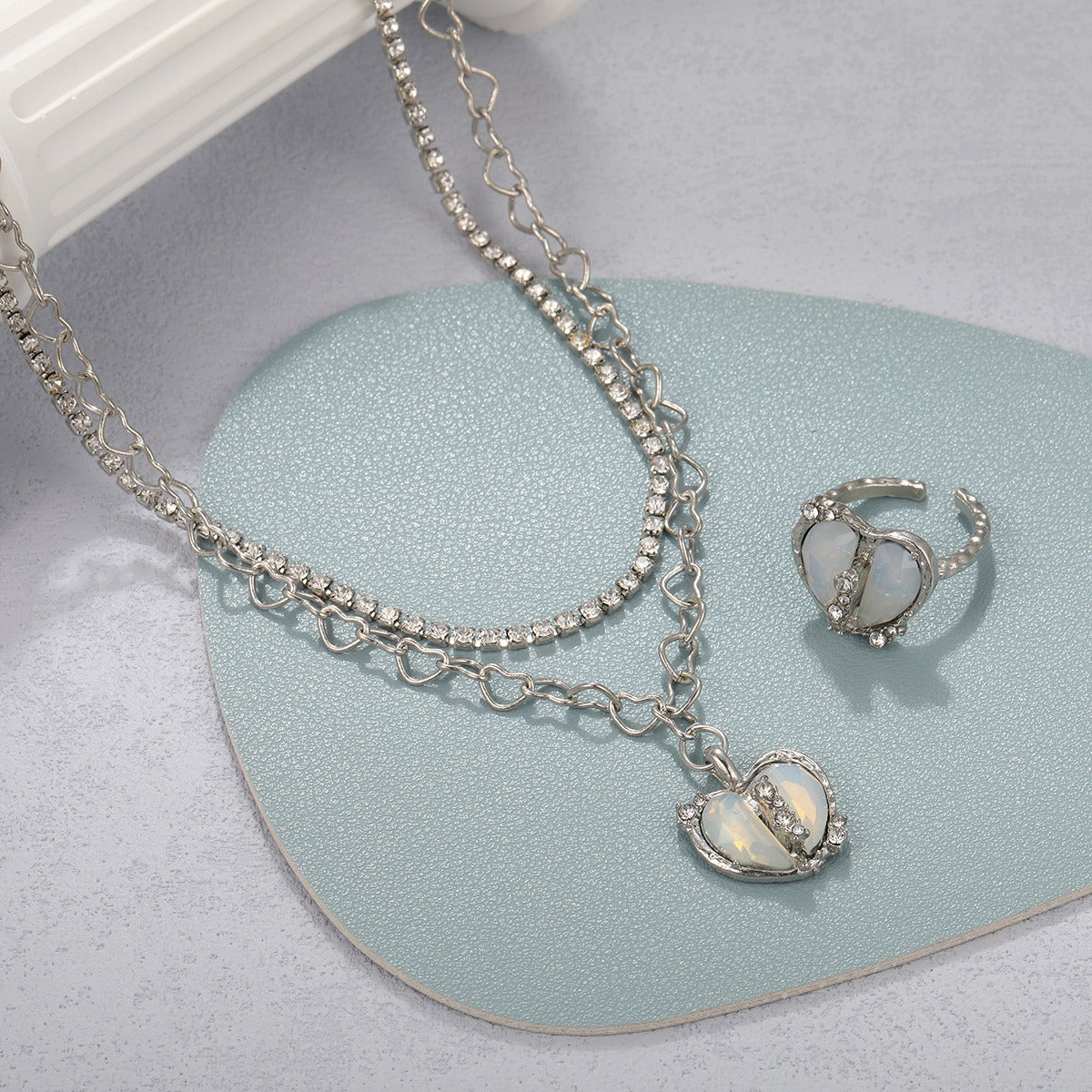 A silver rhinestone-encrusted double necklace and matching ring feature split heart pendants.