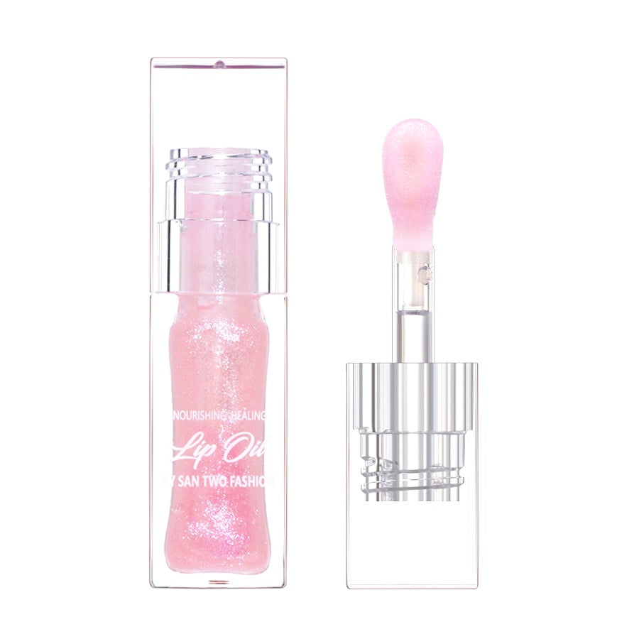 Clear plastic lip oil tube and applicator wand with shimmering pink liquid and white text.