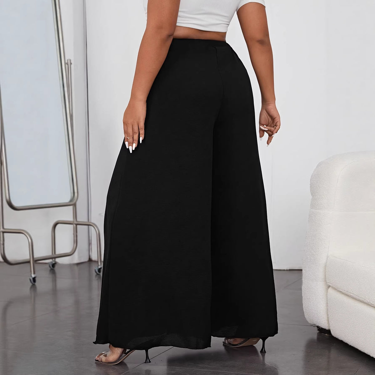 Rear view of black solid wide-leg pants in a lightweight woven fabric, featuring a high elastic waist.