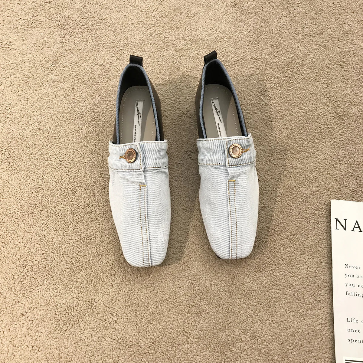 Light blue denim slip-on shoes with square toes, brown heels, and a decorative button on each upper.