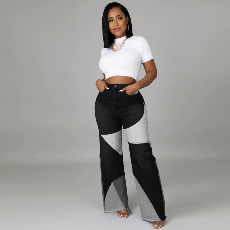 Model wears black, grey, and white patchwork denim wide-leg jeans with raw hems and a white cropped top.