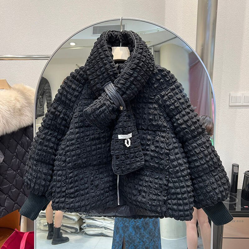 A black textured puffer jacket with a stand collar and matching scarf hangs on a mirror.
