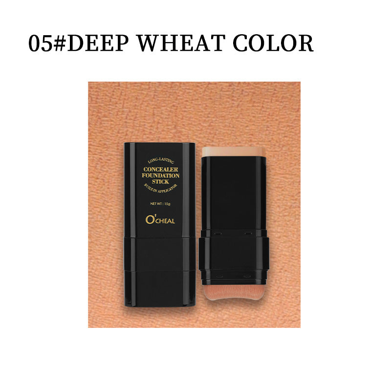 Black plastic concealer foundation stick with gold lettering and built-in brush applicator, in deep wheat color.