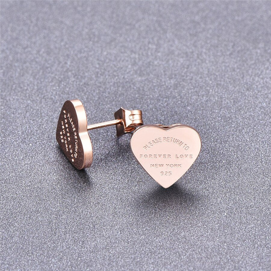 Rose gold heart stud earrings with engraved text "PLEASE RETURN TO FOREVER LOVE NEW YORK 925".