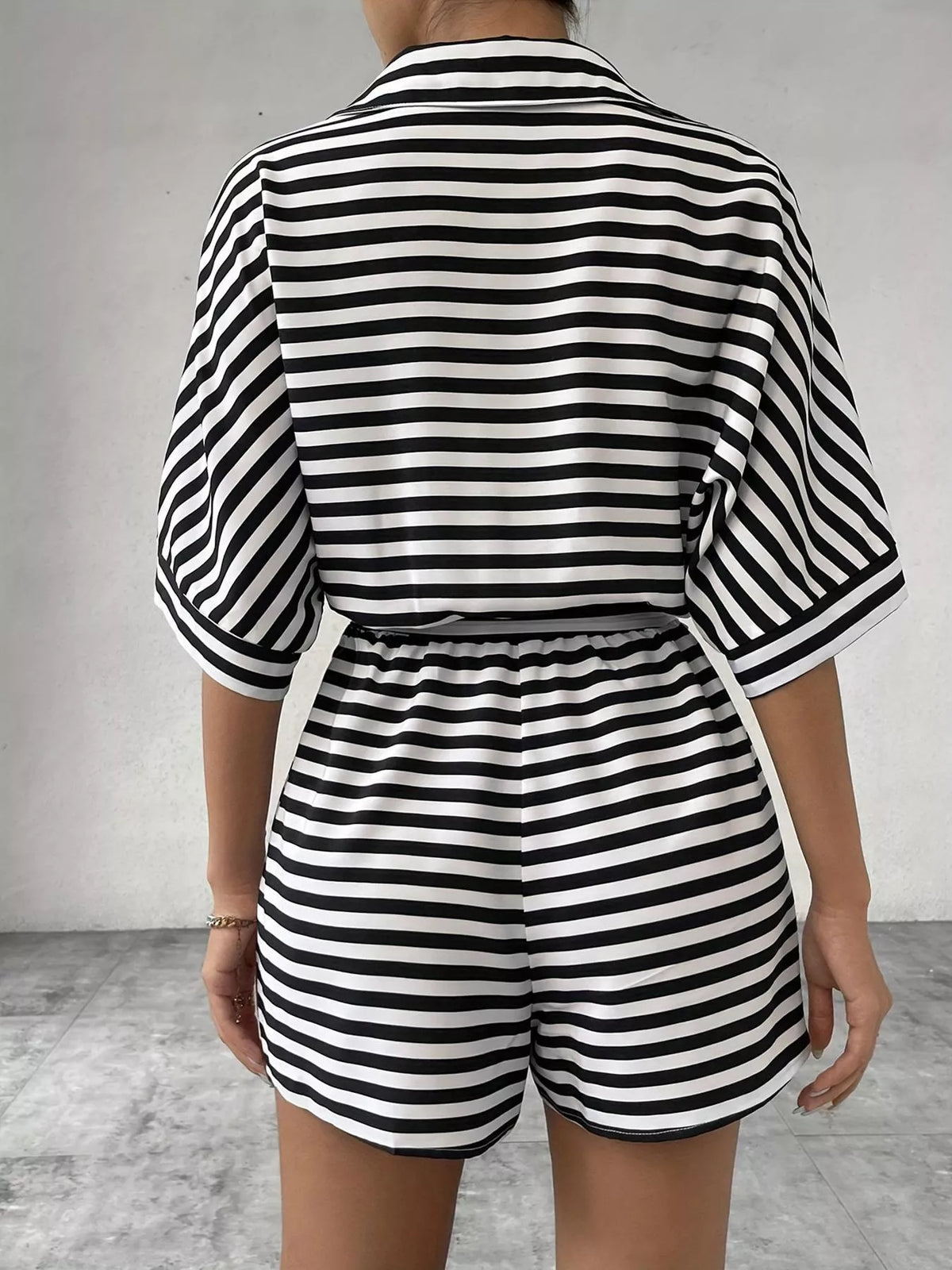 Striped button-up belted romper jumpsuit by Plush Fashion Hub, featuring a stylish design and waist tie detail.