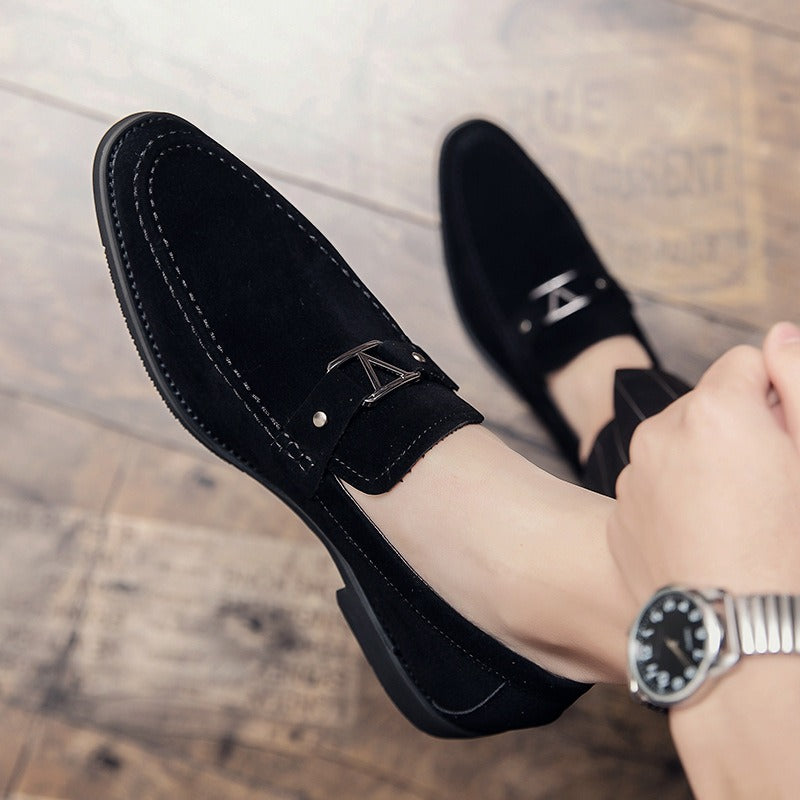 Black suede casual loafers featuring a silver metal buckle and stitch details, worn on a foot.