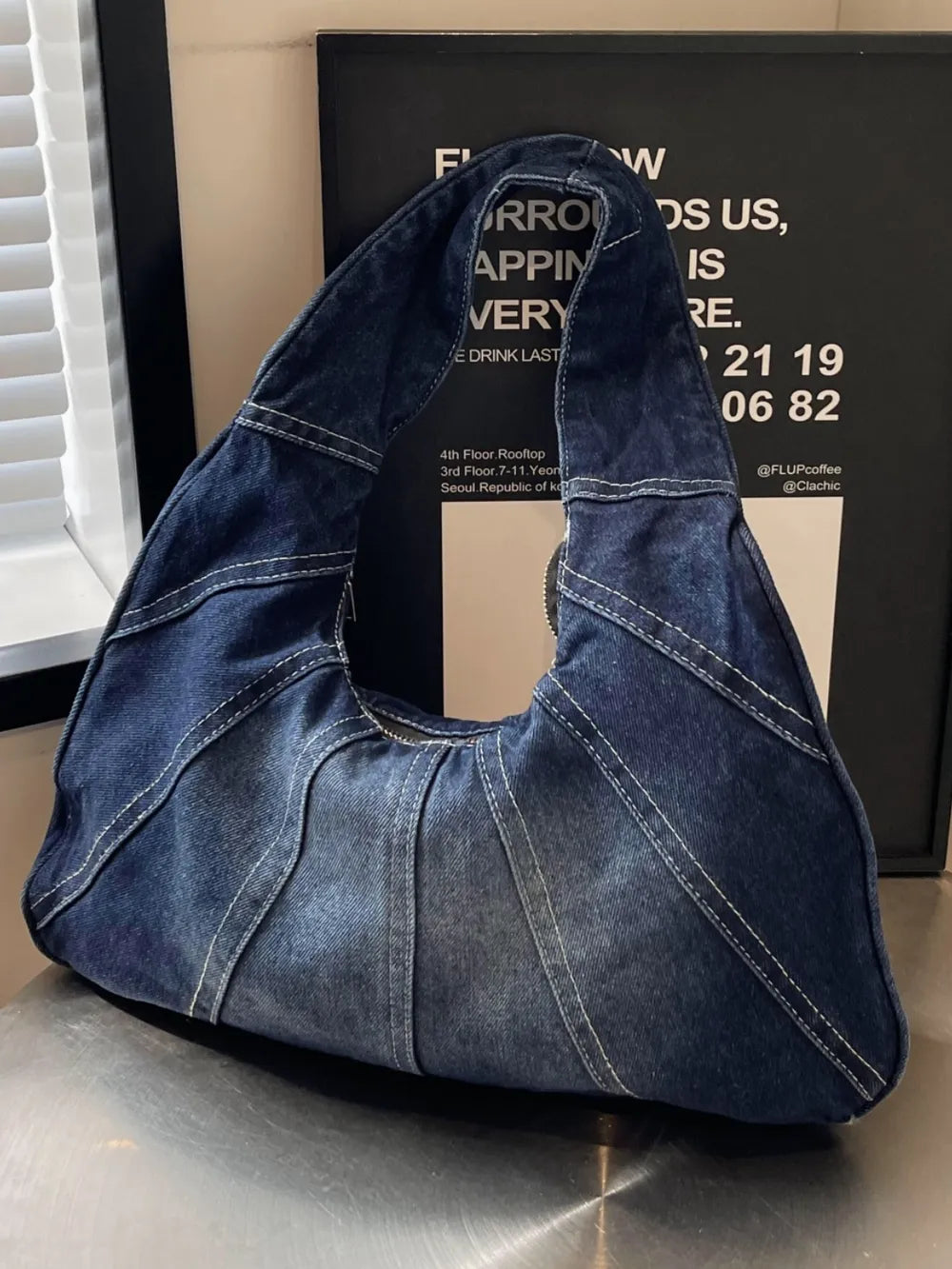 Dark blue denim hobo shoulder bag with white contrast topstitching and panel construction.