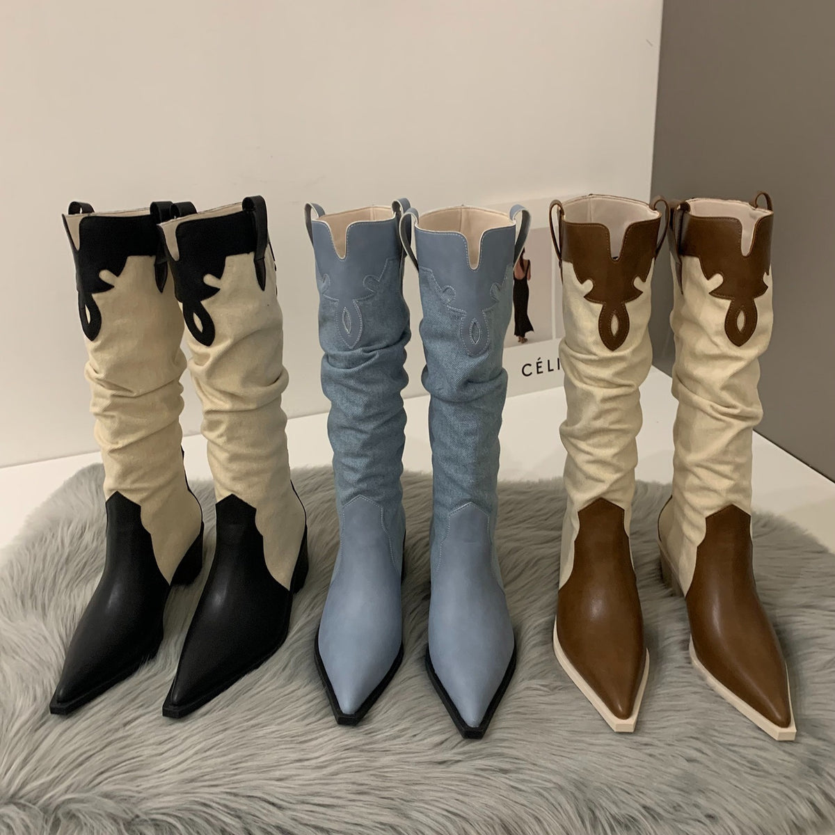 Three pairs of knee-high slouchy cowgirl boots in black/cream, blue, and brown/cream with pointed toes and embroidery.