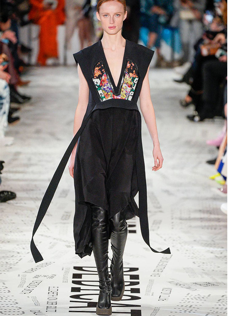 Black sleeveless midi dress with V-neck, floral embroidery inserts, and long side ties worn with black leather boots.