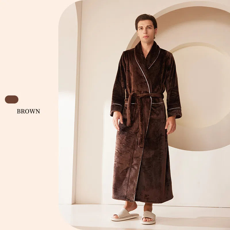 A man wears a brown plush fleece robe with white trim, a shawl collar, a tie belt, and two pockets.