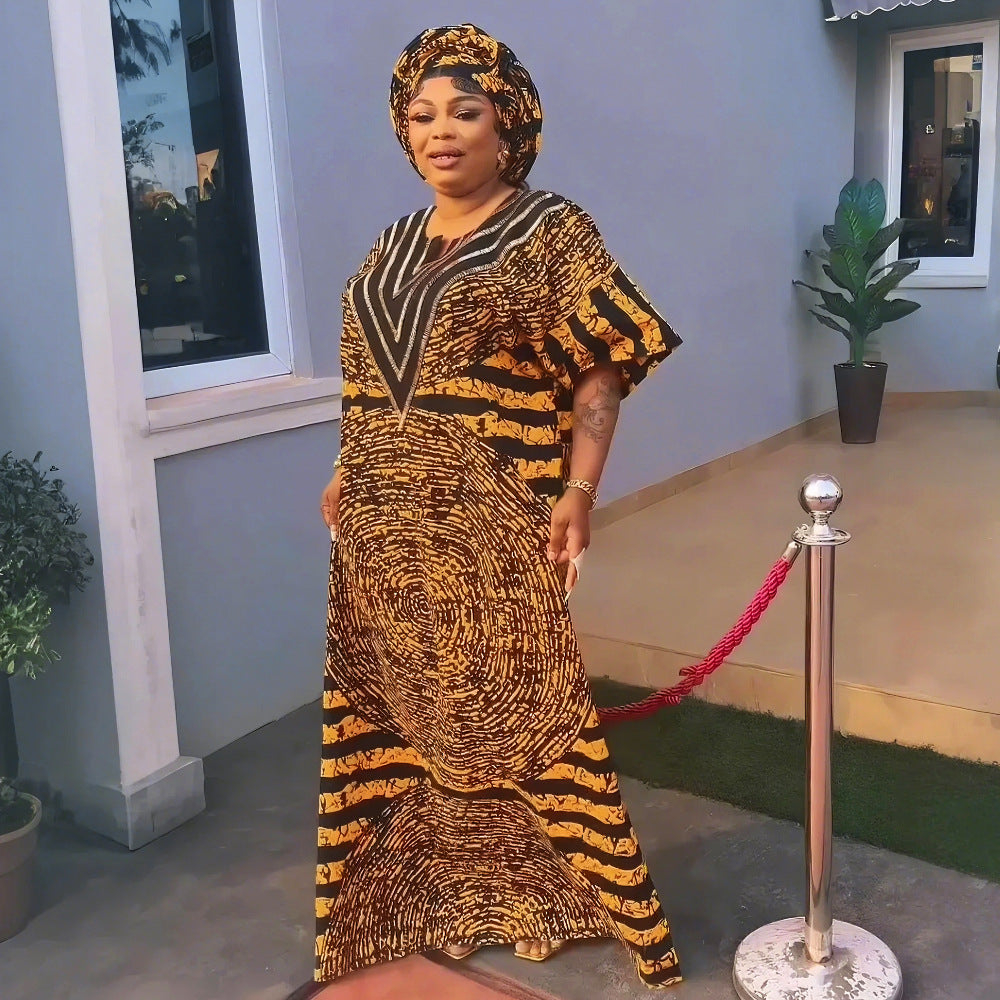 A woman wears a long, loose, black and yellow printed dress and matching headwrap.