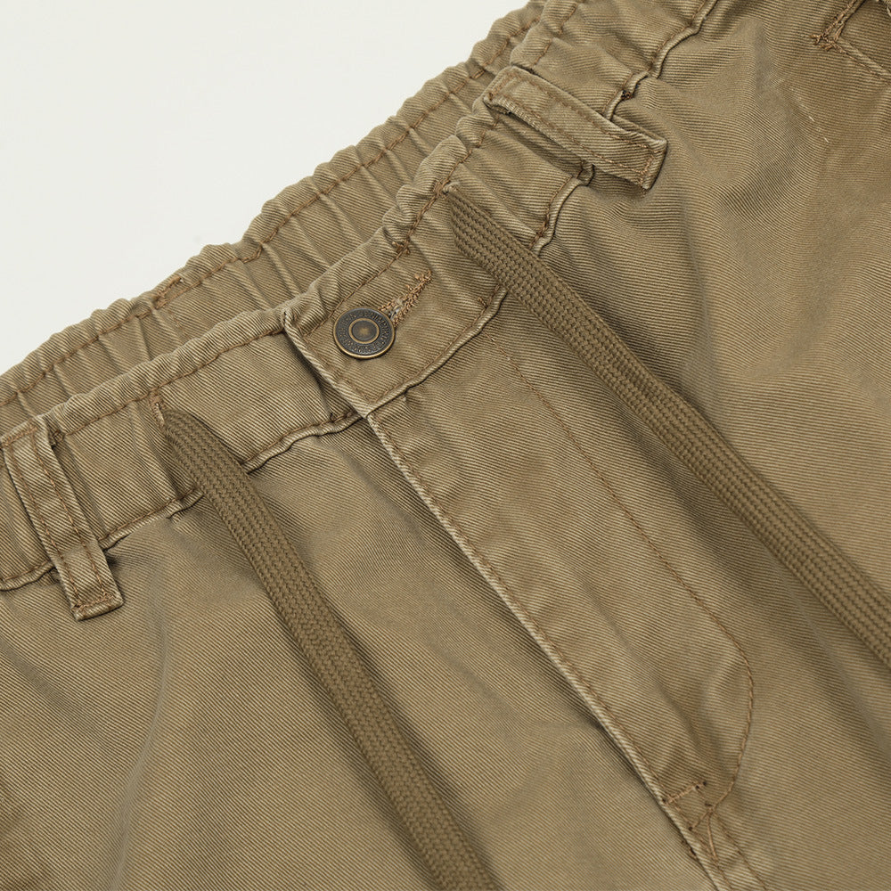 Khaki cotton trousers featuring an elastic waistband, belt loops, drawstring, and button closure.