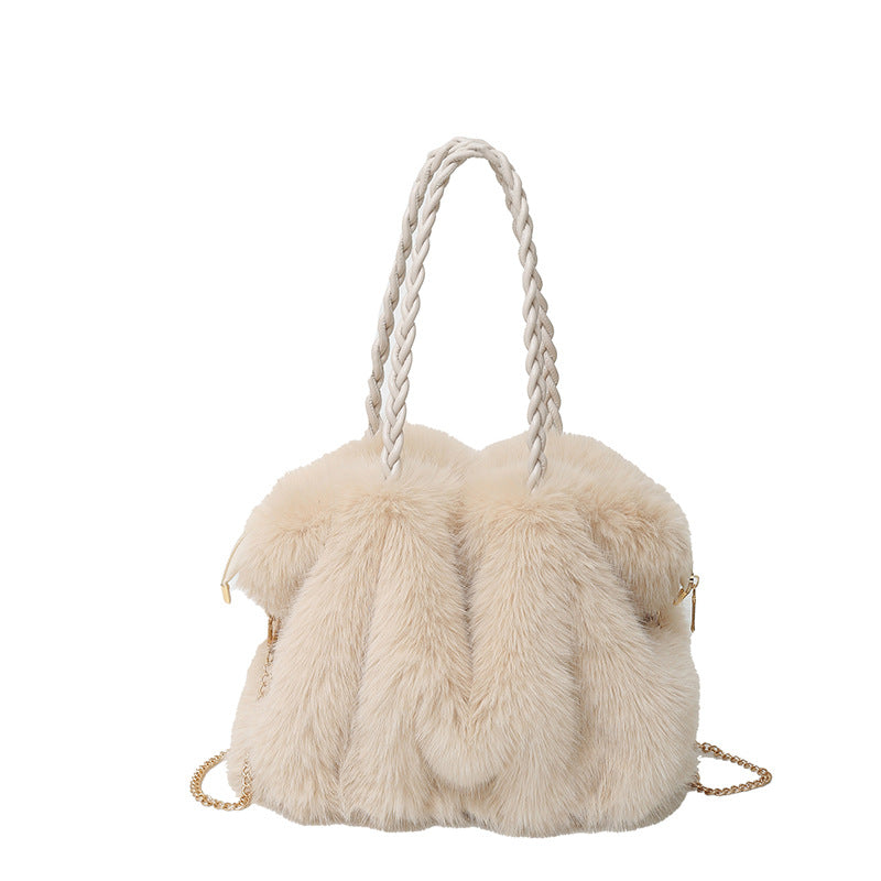 Beige faux fur handbag with braided handles and a detachable gold chain strap on a white background.