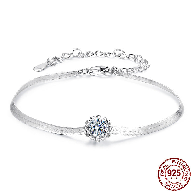 A silver snake-chain bracelet featuring a sparkling flower-shaped centerpiece set with a round stone.