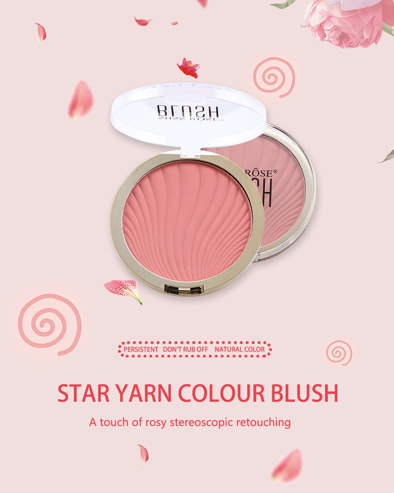Pink pressed powder blush in a round plastic compact with a wave-patterned surface.