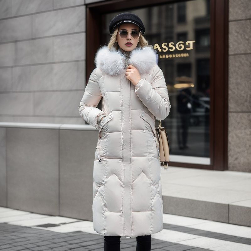 A woman wearing a knee-length, quilted beige coat with a large white fur hood.