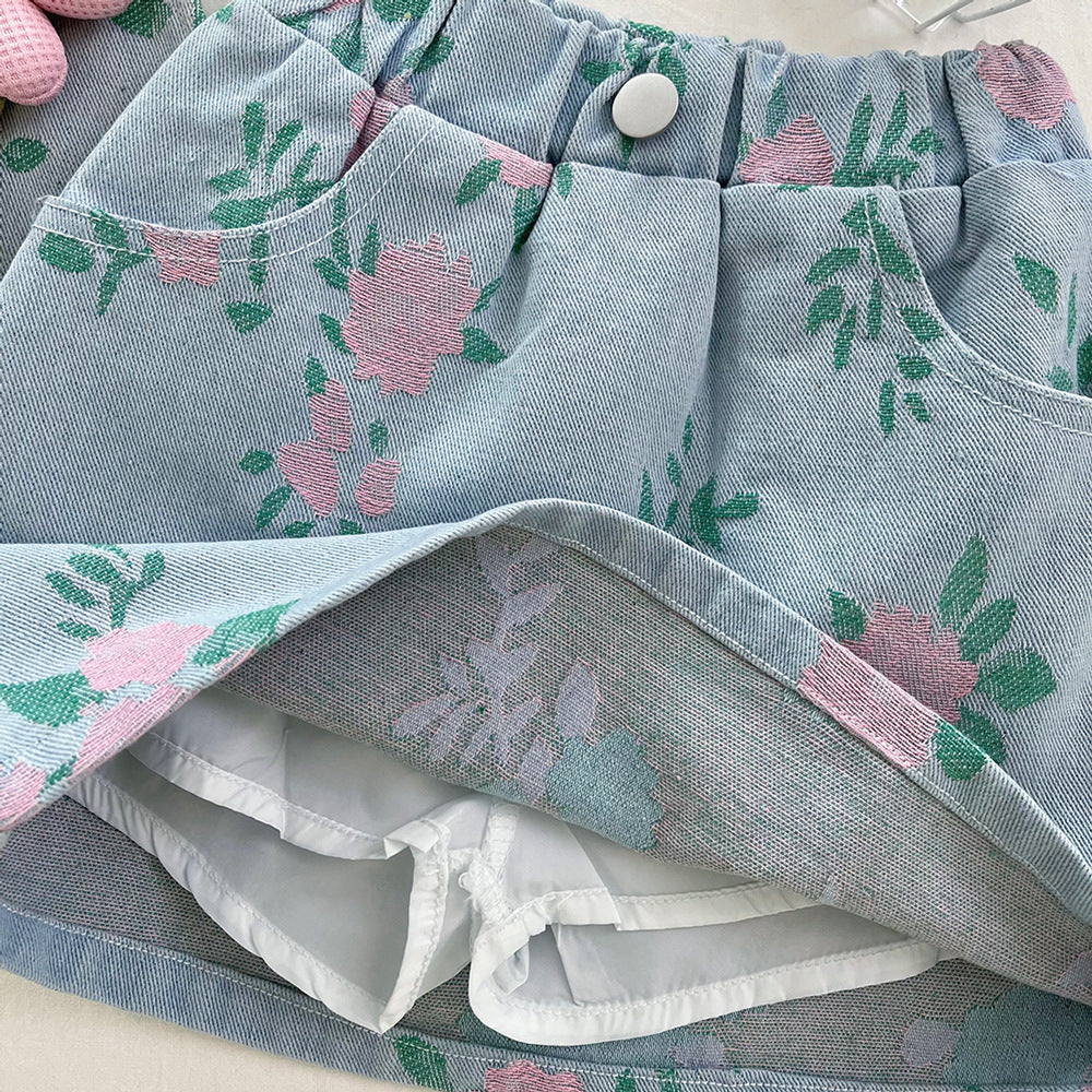 Blue denim skort with pink floral pattern, white inner shorts, elastic waistband, pockets, and a button.