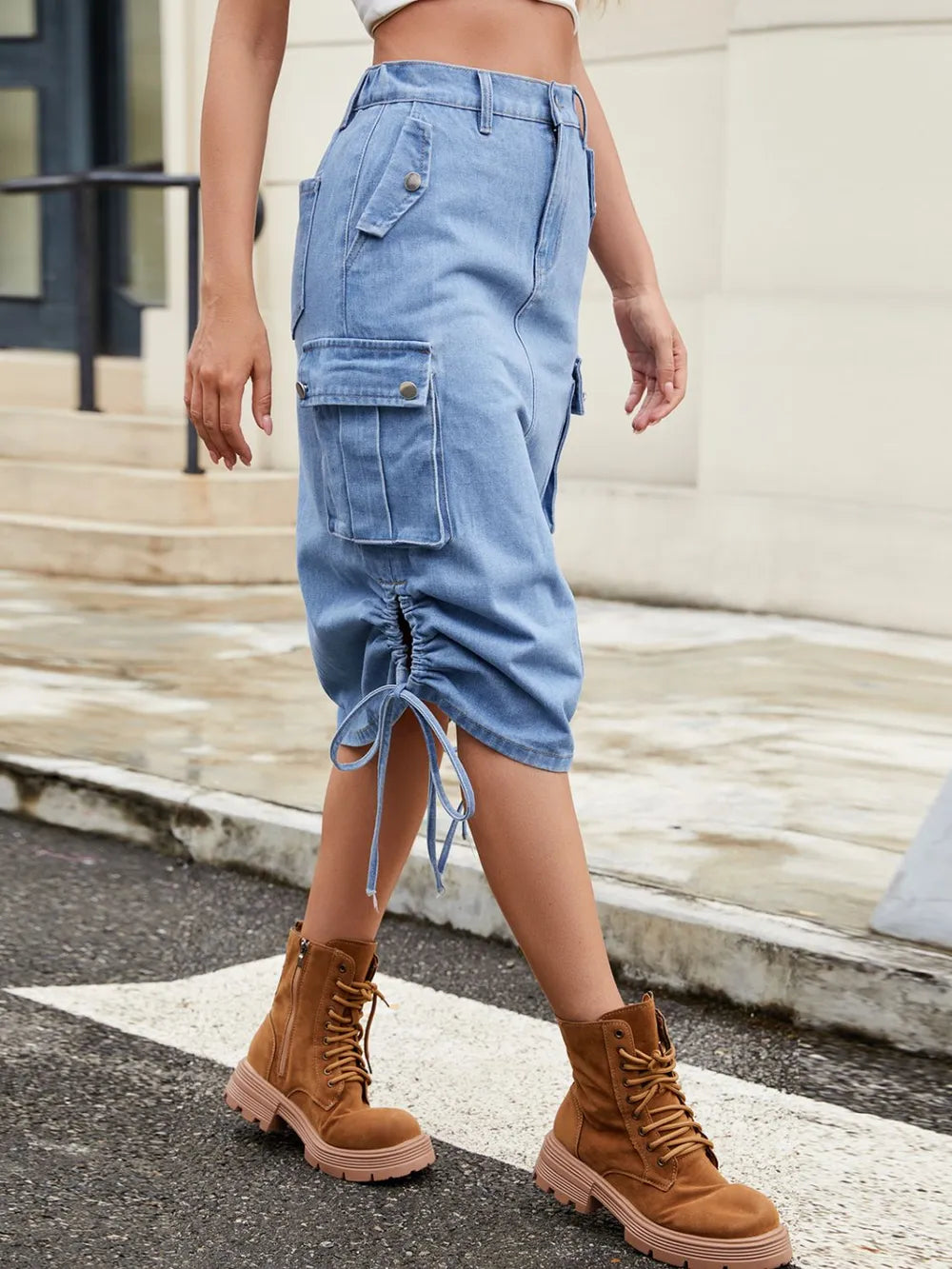 Light blue denim cargo midi skirt with side pockets and a drawstring hem, styled in a casual street look.