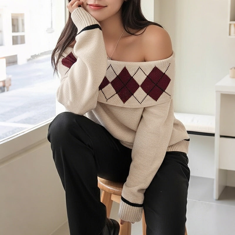 Beige off-shoulder knit sweater with burgundy argyle pattern and black stripe cuffs worn with black pants.
