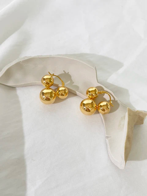 Polished gold-finish metal hoop earrings featuring graduated spherical balls in a clustered cluster design.