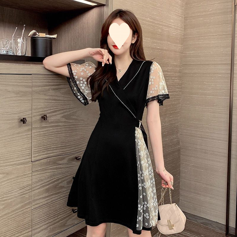Black mini dress featuring sheer mesh sleeves and a side panel with white floral embroidery, plus a v-neckline.