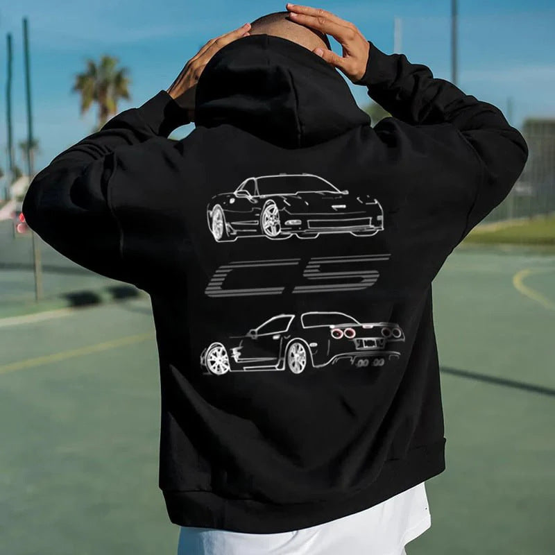 A man wears a black hoodie featuring white line art of a C5 Corvette and the text CS on the back.