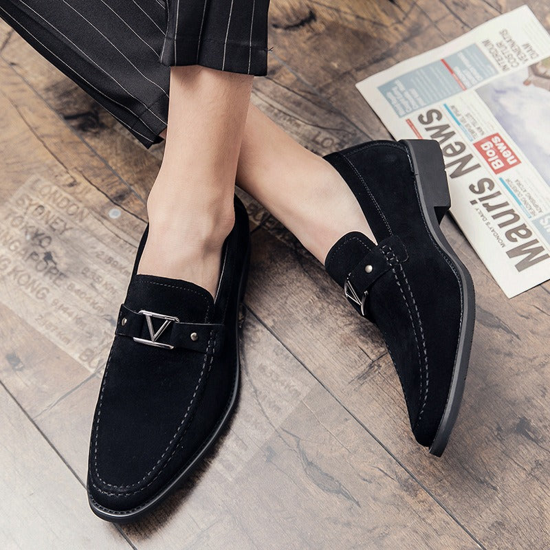 Black suede slip-on dress shoes with a silver V-shaped buckle, visible topstitching, and low heel.