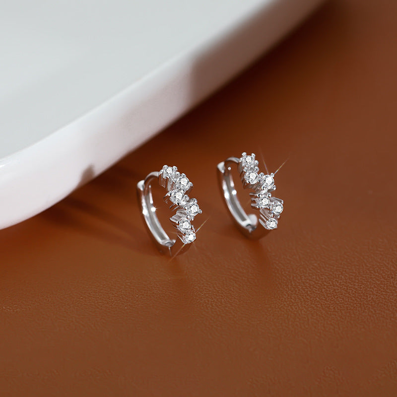 Silver hoop earrings with a cluster of sparkling round gemstones set diagonally along the front.
