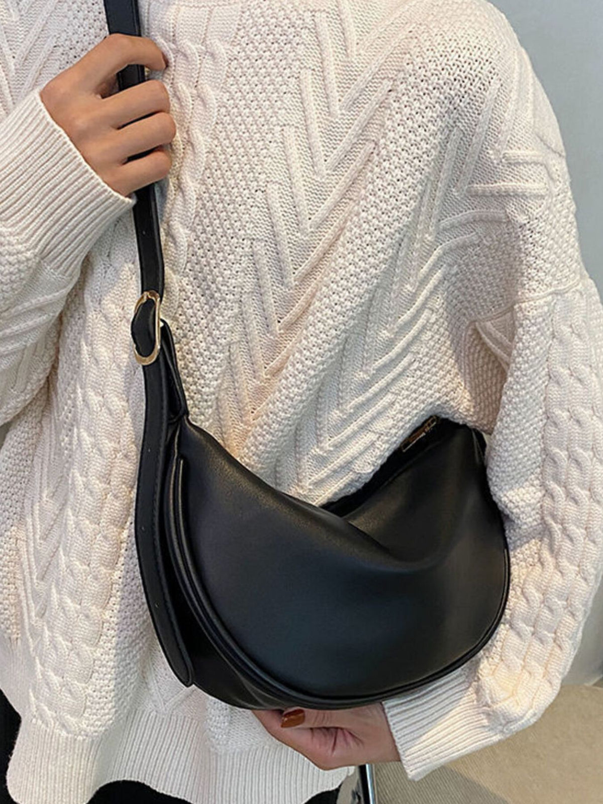Minimalist crescent-shaped crossbody bag in smooth PU leather, featuring a sleek design and adjustable strap.