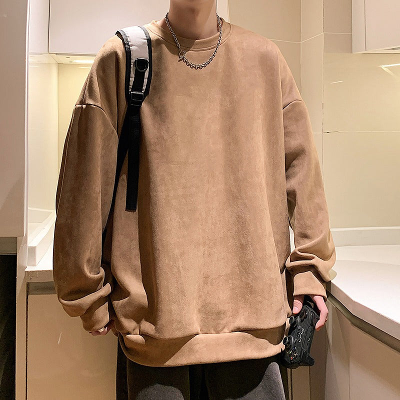 Oversized beige suede crewneck sweatshirt with long sleeves and ribbed cuffs, worn casually.