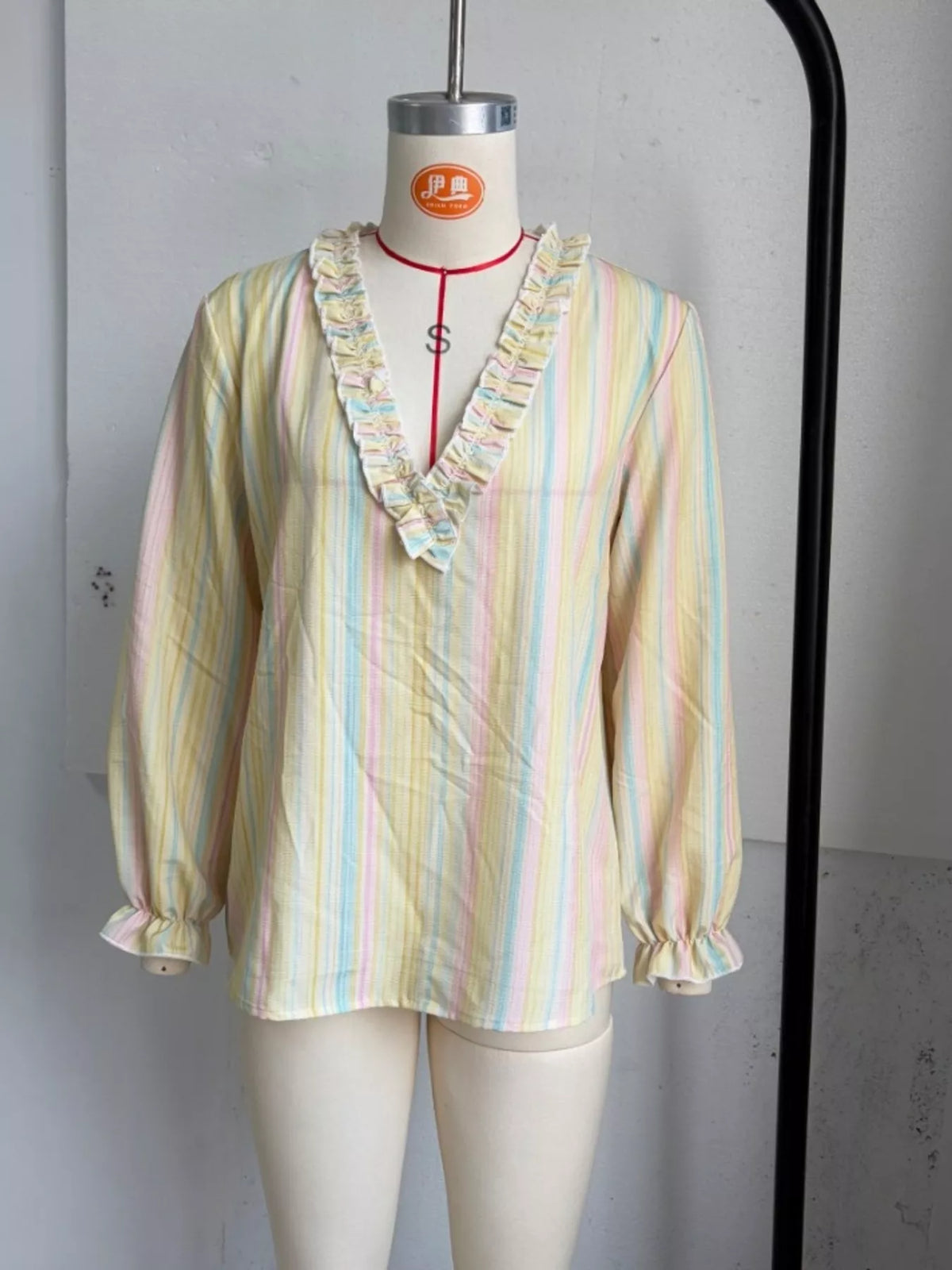 Striped ruffle-trim V-neck blouse by Trendsi featuring a feminine design and stylish details, shown in the product image.