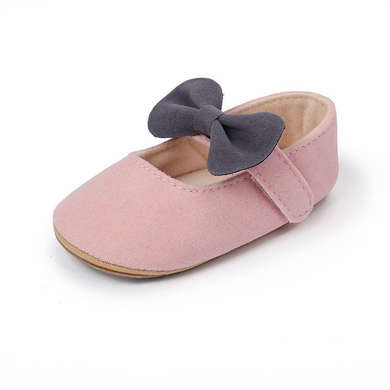 Pink suede baby shoe with a grey bow on the strap, plain pattern, flat style.