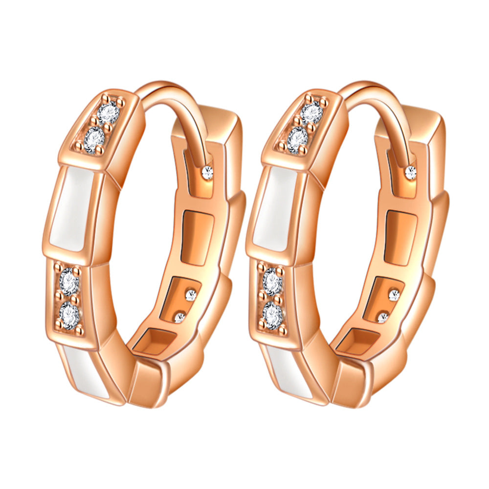 Rose gold hoop earrings with white enamel panels and small crystals in a faceted, geometric style.