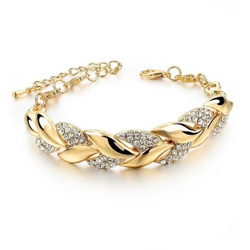 Gold-plated metal link bracelet featuring alternating polished leaf shapes and pavé crystal-set links.