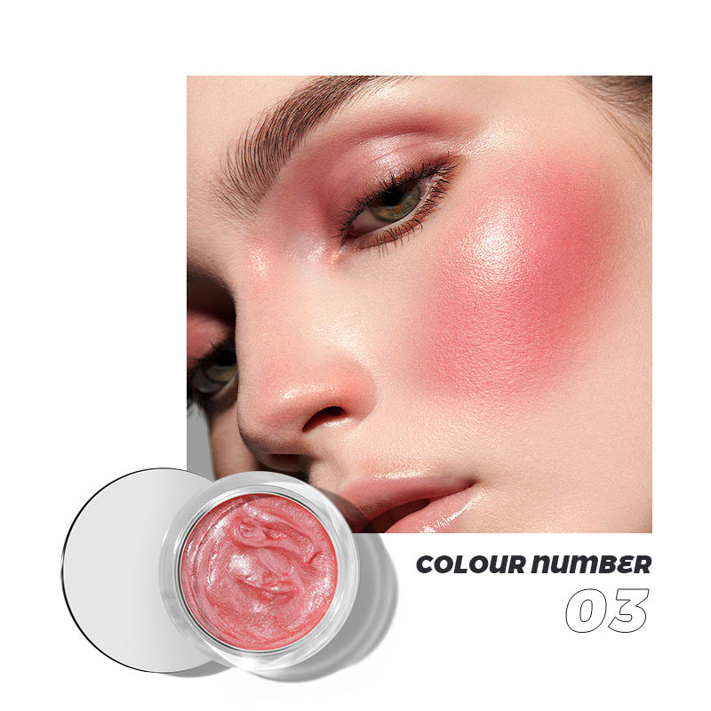 Pink cream blush in a clear glass jar with number 03, shown applied on a model's cheek and eyelids.