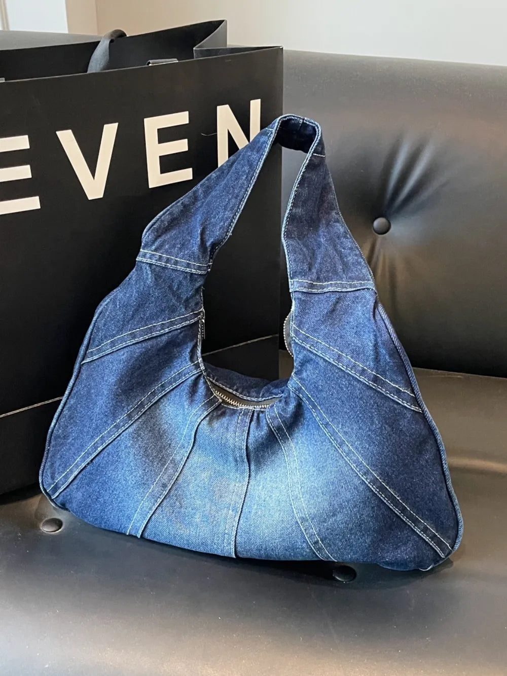Dark blue denim hobo shoulder bag with white topstitching and a top zipper.