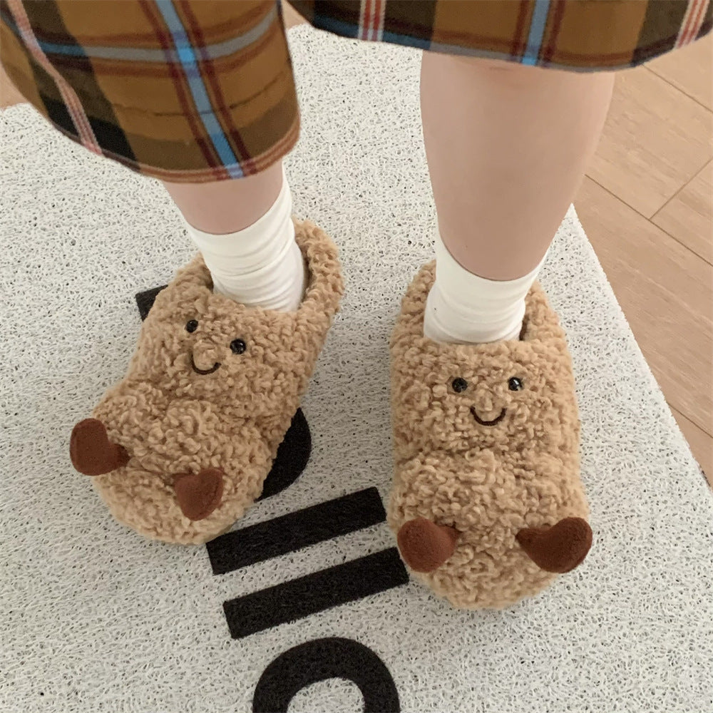 Brown fuzzy plush slippers with embroidered smiley faces and little brown feet details, worn with white socks.