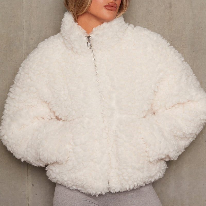 A person wears a fluffy white fleece jacket with a high collar and a front zipper.