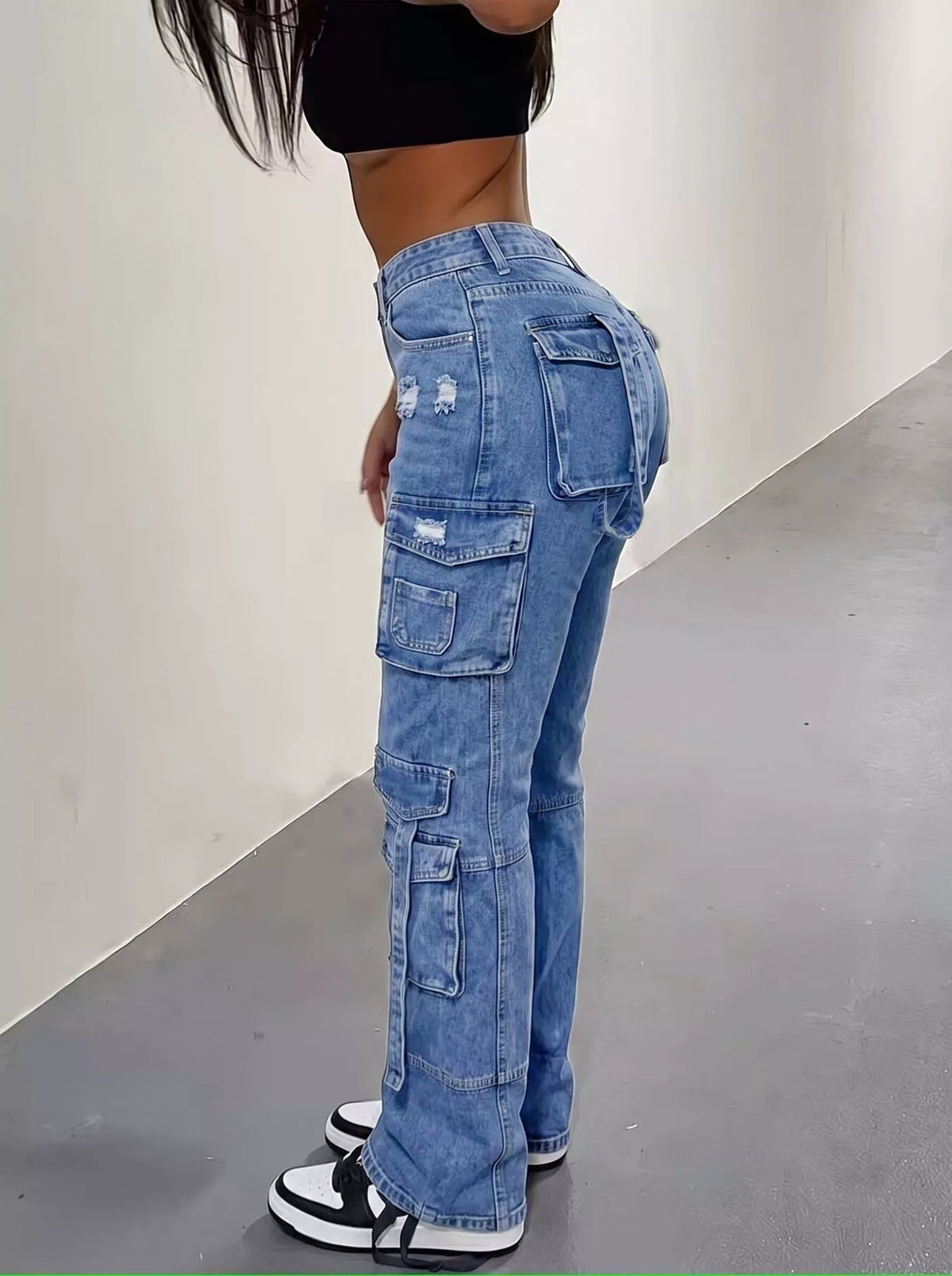 High-waisted distressed cargo jeans by Trendsi featuring a relaxed fit, multiple pockets, and ripped details on light denim fabric.