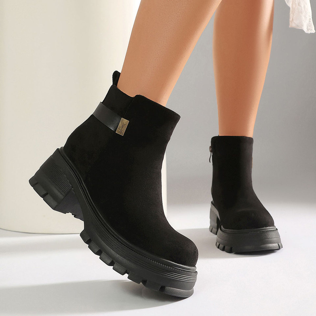 Black suede ankle boots with chunky platform lug soles, a side strap, and metallic side detail.