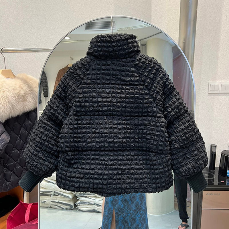 A black textured puffer jacket with a stand collar and ribbed cuffs is shown from the back.