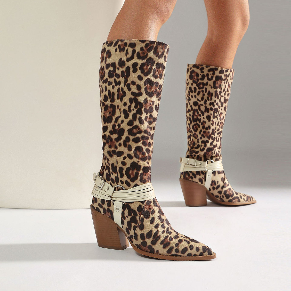 Leopard print faux suede knee-high boots with white buckled ankle straps and stacked heels.