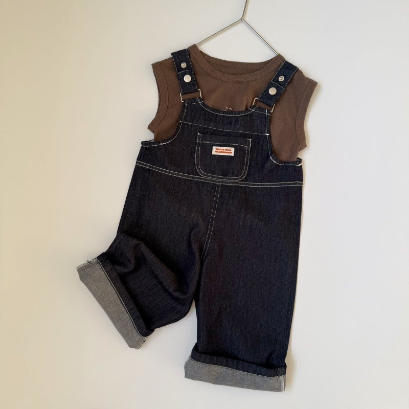 Dark blue denim overalls over brown sleeveless t-shirt, featuring contrast stitching and cuffed hems.