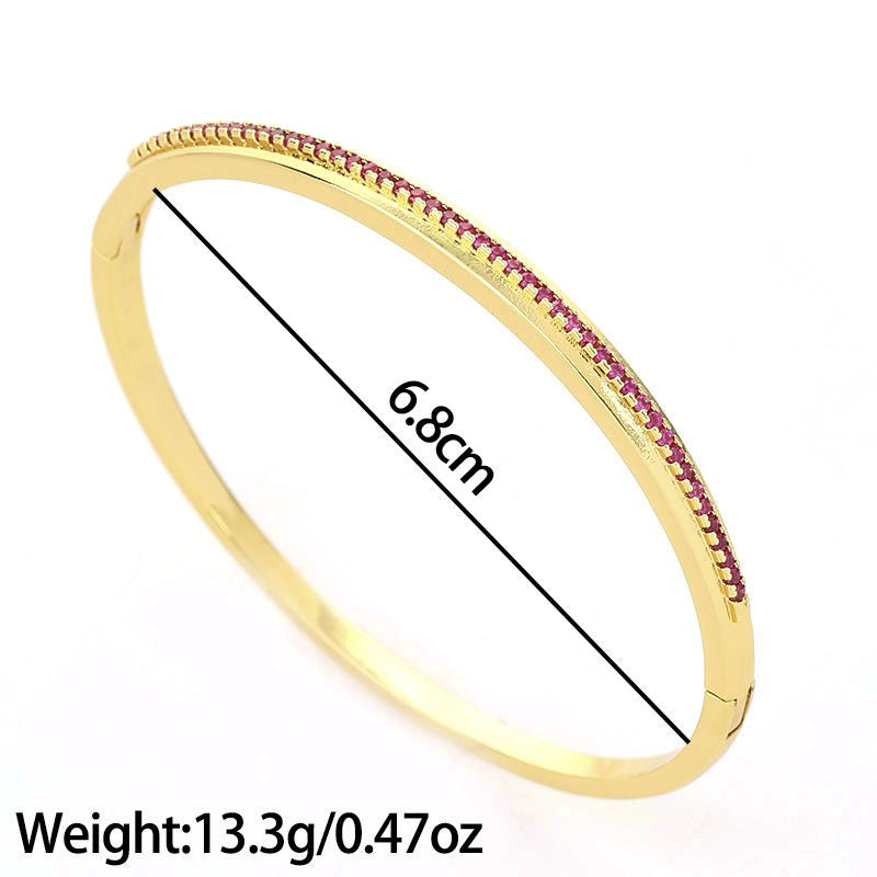 Gold-colored metal bangle bracelet, paved with small pink gemstones along the top edge, width 6.8cm.